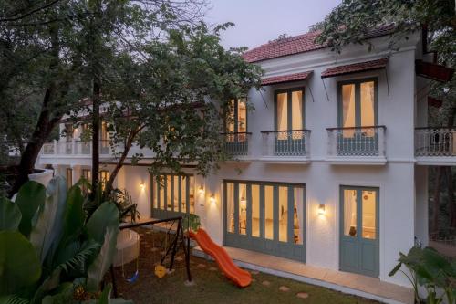 a large white house with windows and an orange slide at Villa Mandarina by The Blue Kite - 4BHK Standalone Luxuxy Villa in Assagao with Large Private Pool, Pool Table, Kids Play Area, Garden, Caretaker & Security in Siolim