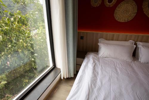 a bedroom with a bed next to a window at 北京沐桐客栈 in Sanduhe