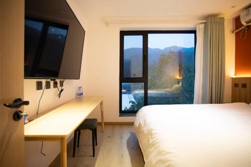 a bedroom with a bed and a desk and a window at 北京沐桐客栈 in Sanduhe