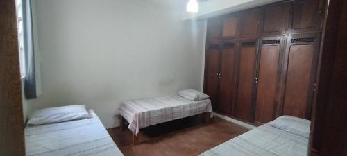 a room with two beds and a wooden cabinet at Hospedaria Central in Lavras