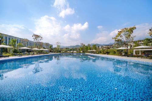 a large swimming pool with chairs and umbrellas at Xikang Wellness & Resort Qingcheng Mountain in Taiping