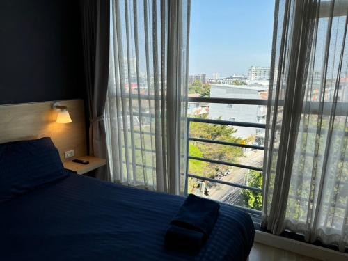 a bedroom with a bed and a large window at GP House Express Sukhumvit 81 in Bangkok