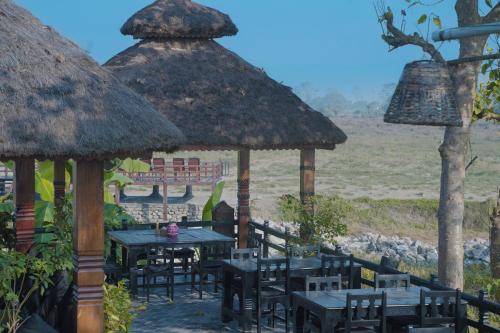 a restaurant with tables and chairs and a thatched roof at Sapana Village Lodge in Sauraha