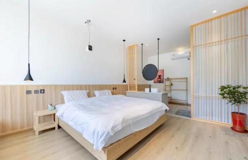 a bedroom with a large white bed and a sink at 北京沐桐客栈 in Sanduhe