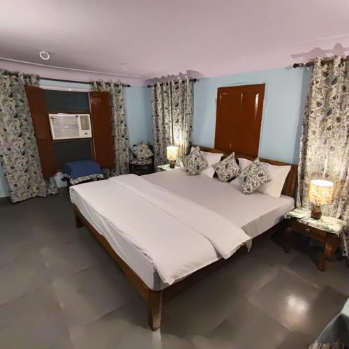 a bedroom with a large bed with two lamps and curtains at Marwa House in Jaipur