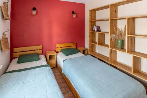 two beds in a room with a red wall at Folwark Wierzchy in Wierzchy