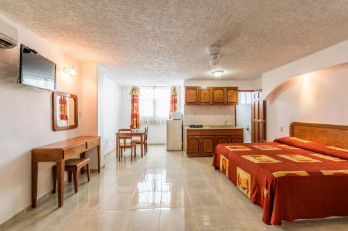 a bedroom with a bed and a desk and a kitchen at Suites Poliforum Inn in León