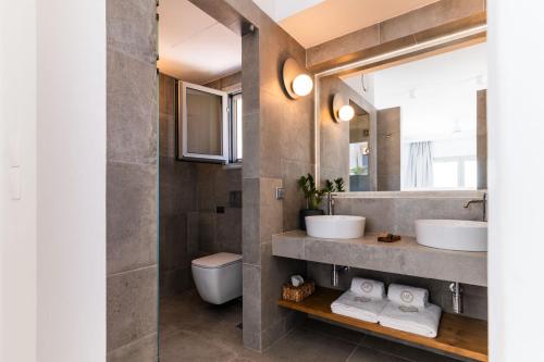 a bathroom with two sinks and a toilet at Makrikythera Luxury Suites - Private Pool or Hot Tub Suites in Dhiakofti