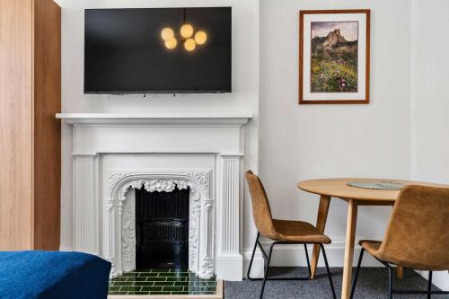a living room with a fireplace with a tv above it at Portsea Place - Chic queen studio and parking in Hobart