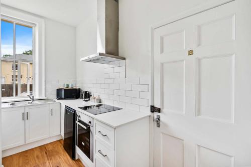 a kitchen with white cabinets and a white door at Portsea Place - Chic queen studio and parking in Hobart