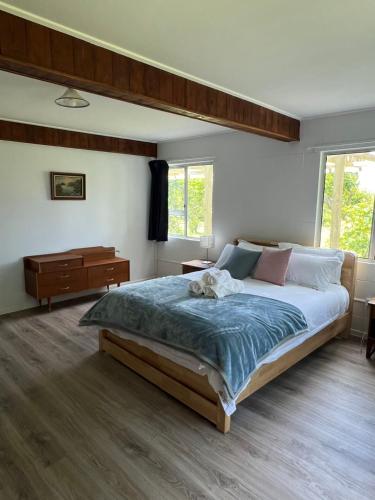 a bedroom with a large bed and a dresser at Twinkle Orchard Camp in Taupaki