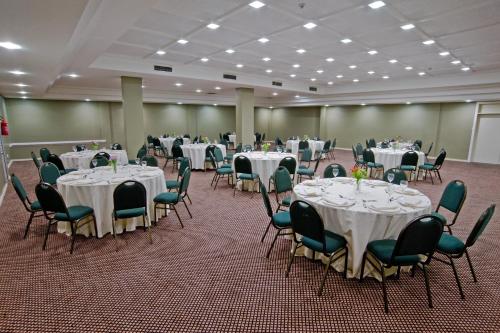 a banquet hall with white tables and chairs at Wyndham Golden Foz Suítes in Foz do Iguaçu