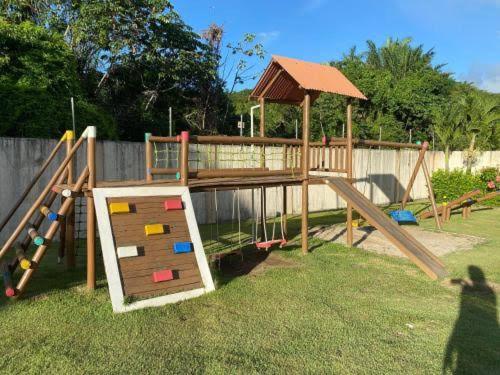 a wooden playground with a slide and a gazebo at Apartamento Cantinho na Praia in Ilhéus