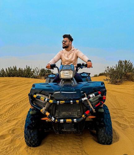 a man riding a quad bike in the sand at Jaisalmer Sand Dunes Luxury Camp And Resort in Jaisalmer