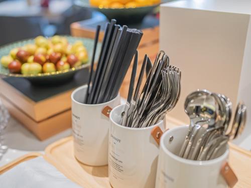 a group of utensils in cups on a table with a bowl of fruit at Xiangyang Station Minfa World City Yishang Plus Hotel in Xiangyang