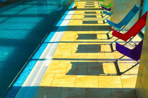 a swimming pool with red and blue chairs next to it at Camves Inn in Sighetu Marmaţiei
