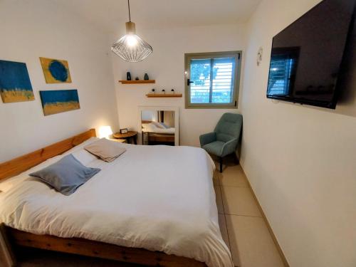 a bedroom with a bed and a green chair at Tavor view נוף תבור in Daverat