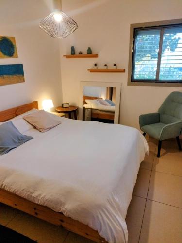 a bedroom with a bed and a chair and a window at Tavor view נוף תבור in Daverat