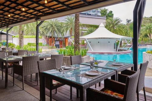 einen Essbereich im Freien mit Tischen und Stühlen sowie einen Pool in der Unterkunft Patong Bay Hill in Patong Beach