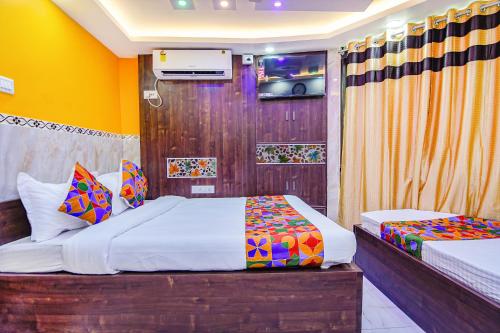 a bedroom with two beds and a tv on the wall at FabHotel MN International - Nr Park Circus in Kolkata