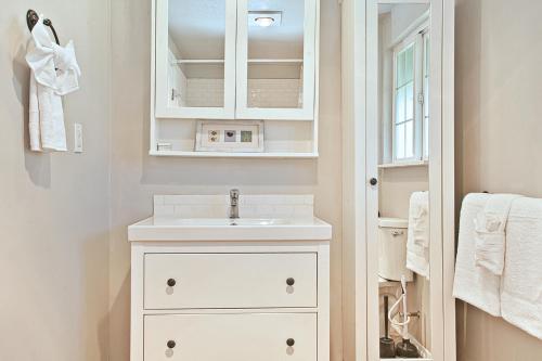 Baño blanco con lavabo y espejo en Ten Pines Cottage, en Ocean Shores