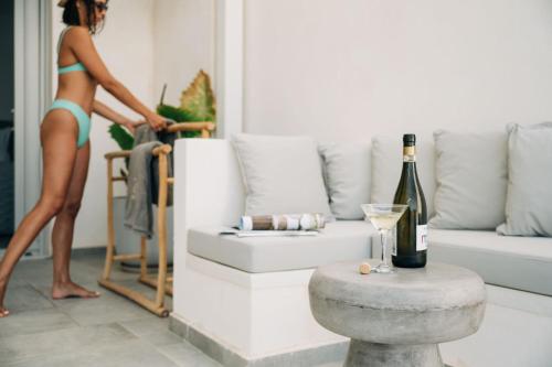 a woman in a bikini in a living room with a bottle of wine at Makrikythera Luxury Suites - Private Pool or Hot Tub Suites in Dhiakofti