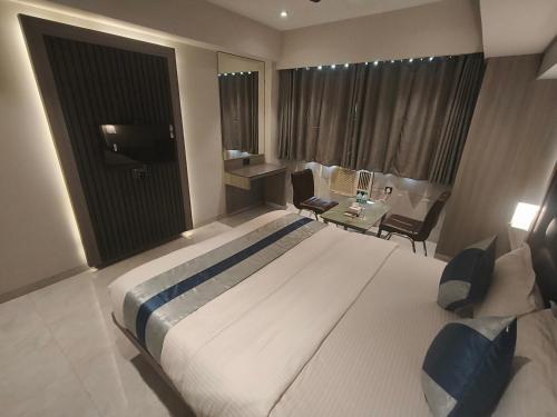 a hotel room with a large bed and a desk at Nakshtra Residency Kalyan in Kalyan