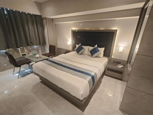 a hotel room with a large bed and a desk at Nakshtra Residency Kalyan in Kalyan
