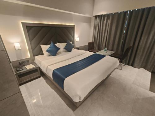 a hotel room with a large bed with blue pillows at Nakshtra Residency Kalyan in Kalyan