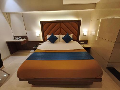 a bedroom with a large bed with blue pillows at Nakshtra Residency Kalyan in Kalyan