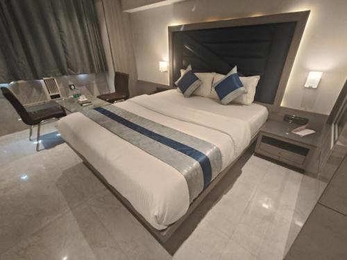 a hotel room with a large bed and a desk at Nakshtra Residency Kalyan in Kalyan