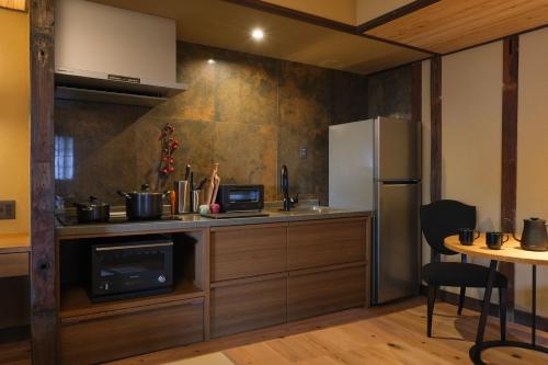 a kitchen with a counter and a refrigerator and a table at Tomonoura Shiomachi Hotel in Fukuyama