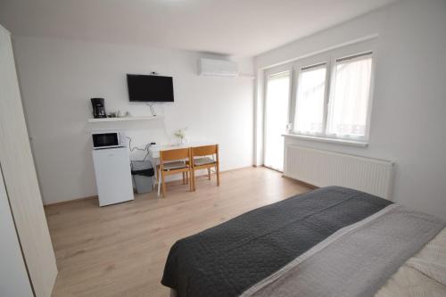 a bedroom with a bed and a table with a chair at Omni Residence Vendégház in Bük
