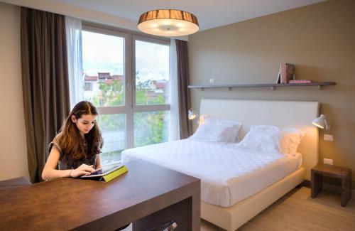 a woman sitting in front of a bed with a book at Forte16 View & SPA in Florence