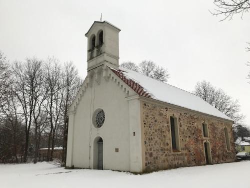 a small white church with snow on the ground at Romantische Ferienwohnung im Herrenhaus Wüstenhain Spreewald in Vetschau