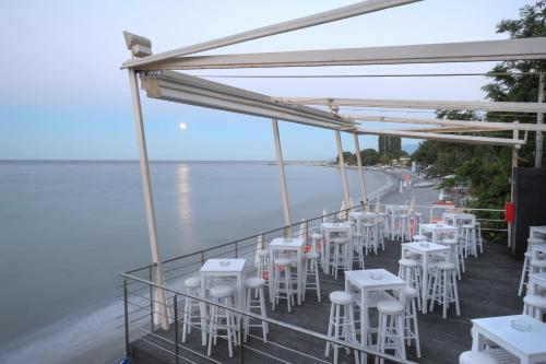 a row of white tables and chairs on a balcony overlooking the ocean at Olympos Beach in Plaka Litochorou