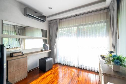 a living room with a large window and a wooden floor at The Height Khaoyai Resort in Ban Huai Sok Noi