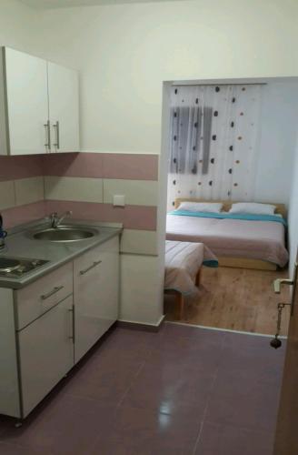 a kitchen with a sink and a bed in a room at Guest House Oleander in Petrovac na Moru