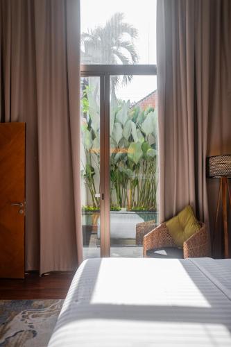 a bedroom with a bed and a large window at Kayumas Seminyak Resort in Seminyak