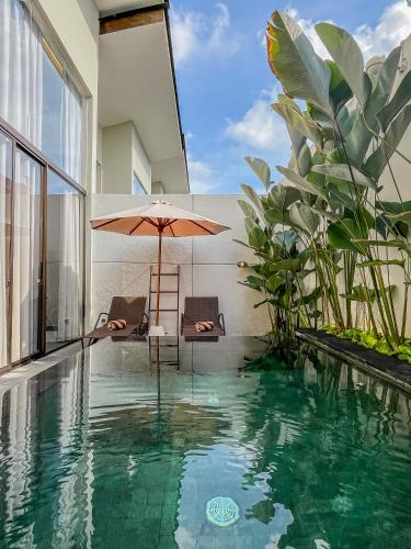 a pool with two chairs and an umbrella in a house at Kayumas Seminyak Resort in Seminyak