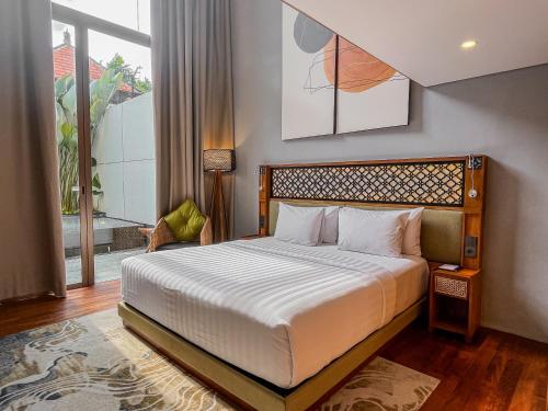 a bedroom with a bed and a window at Kayumas Seminyak Resort in Seminyak