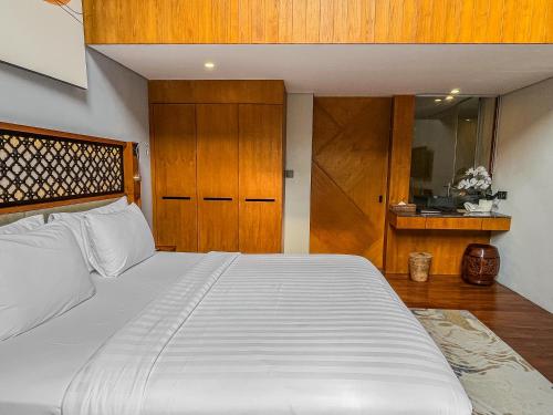 a bedroom with a large white bed and wooden cabinets at Kayumas Seminyak Resort in Seminyak