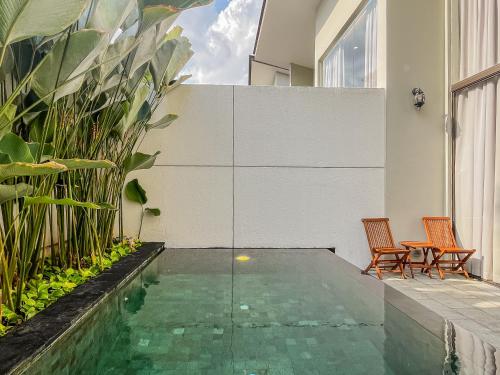 a pool in the middle of a house with two chairs at Kayumas Seminyak Resort in Seminyak