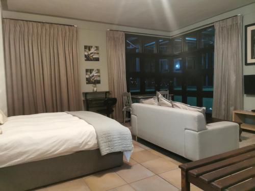 a bedroom with a bed and a couch and a window at Mordillo House in Johannesburg