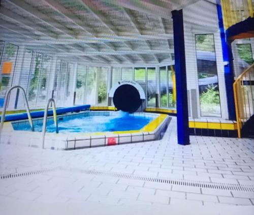 a swimming pool in a building with a window at Knusse bungalow met binnen en buitenzwembad op het park in Ermelo