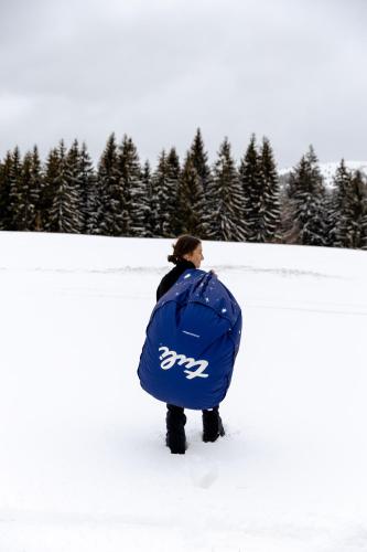 a person standing in the snow with a blue bag at Wild House Donovaly in Donovaly