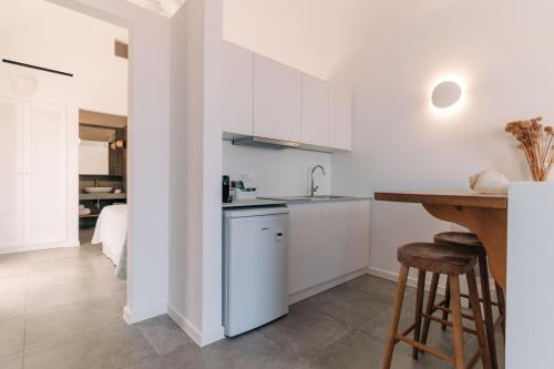 a kitchen with white cabinets and a wooden table at Makrikythera Luxury Suites - Private Pool or Hot Tub Suites in Dhiakofti