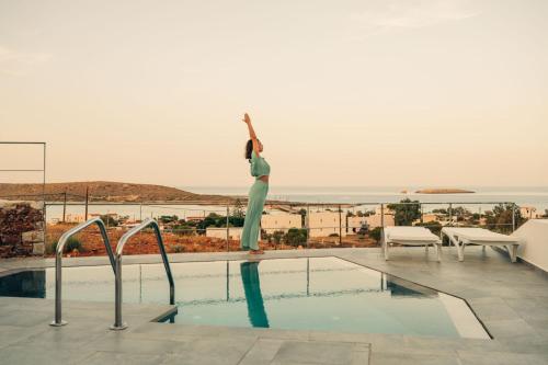 a woman is standing on the edge of a swimming pool at Makrikythera Luxury Suites - Private Pool or Hot Tub Suites in Dhiakofti