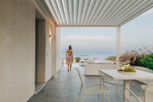 a woman walking down a balcony with a table and chairs at Makrikythera Luxury Suites - Private Pool or Hot Tub Suites in Dhiakofti