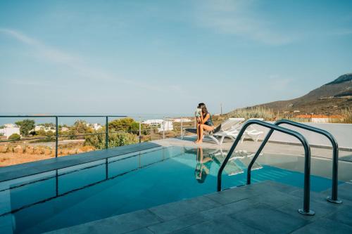 a woman sitting on the edge of a swimming pool at Makrikythera Luxury Suites - Private Pool or Hot Tub Suites in Dhiakofti